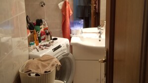 A compact bathroom with a toilet, washing machine, and sink.