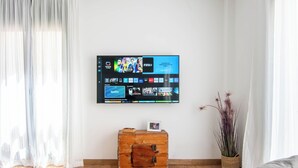 A living room with a flat-screen TV mounted on the wall displaying various streaming services. - Apartamentos Haro (Haro)