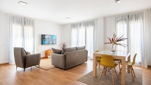A modern living room with a sofa, chairs, a dining table, and a TV. - Apartamentos Haro (Haro)