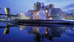 A modern building with a unique architectural design, featuring multiple curved and angular structures, situated near a body of water reflecting its image. - Apartamentos Haro (Haro)