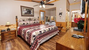Ein Schlafzimmer mit einem hölzernen Bett, einem Deckenventilator, einem Nachttisch, einer Lampe und einem Spiegel.