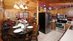Ein Holzblockhaus-Interieur mit Essbereich, Küche und einem Weihnachtsbaum.