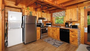 Cucina compatta con mobili in legno, frigorifero in acciaio inossidabile, forno a microonde, piano cottura e lavastoviglie.