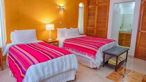A hotel room with two beds, a nightstand with a lamp, a wooden wardrobe, and a small bench. - Beautiful pool side ground floor unit with direct beach access , WiFi and AC. (Akumal)