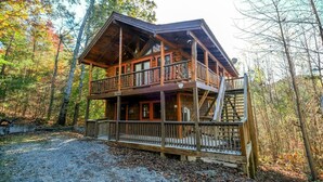 A two-story log cabin with a balcony, surrounded by trees. - First Flight - Pool Table & Hot Tub! (Sevierville)