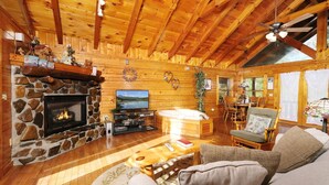 A cozy log cabin interior with a stone fireplace, a television, and a comfortable seating area. - First Flight - Pool Table & Hot Tub! (Sevierville)