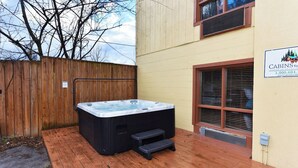 A hot tub on a wooden deck next to a building with a sign reading "Cabins for Vacation".