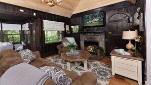 A cozy living room with a fireplace, comfortable seating, and a television mounted above it.
