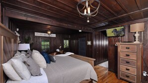 A cozy bedroom with a large bed, a wooden dresser, and a chandelier.