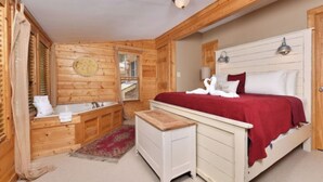Un dormitorio de cabaña de madera con una cama, un banco de madera pequeño, una bañera y una alfombra roja.