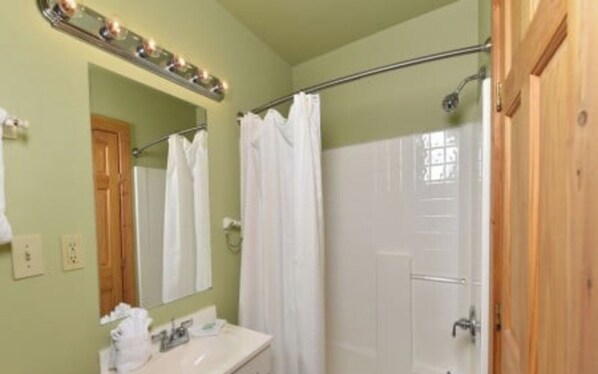 Un bagno con doccia, lavandino e specchio con illuminazione soprastante.