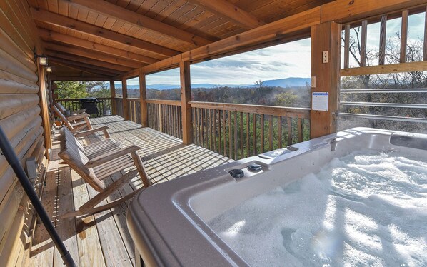 A wooden deck with a hot tub, wooden chairs, and a view of mountains. - Pioneer Place - Arcade Games, Mountain Views, Hot Tub (Sevierville)