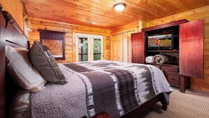 Un dormitorio rústico tipo cabaña de madera con una cama, un televisor y un armario de madera.