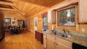 Interior de una cabaña de madera con cocina, comedor y un árbol de Navidad.