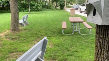 A park with picnic tables and benches, surrounded by trees.
