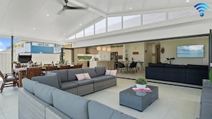 Un espacio habitable amplio con un sofá gris, una mesa de comedor y una cocina al fondo.