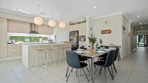 Una cocina moderna con una isla central, taburetes de bar y un comedor con sillas.