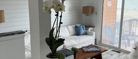 A modern living room with a white sofa, a coffee table, and a potted orchid.