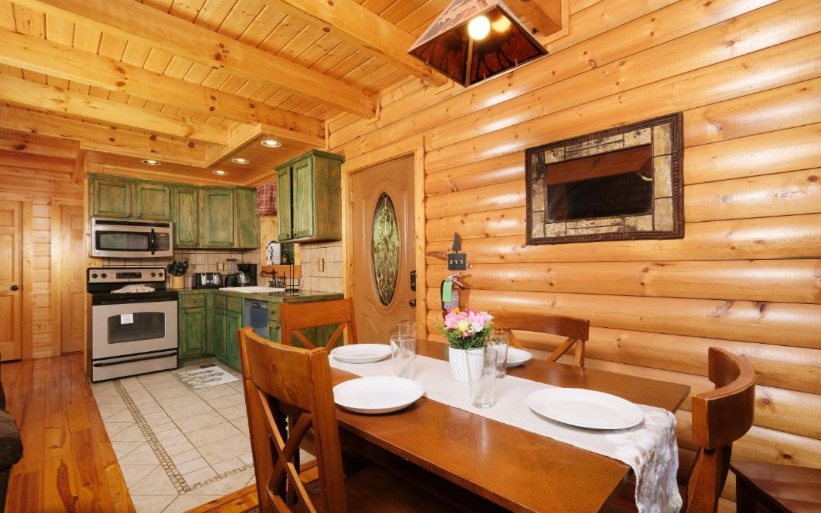 Interior de una cabaña de madera con comedor, cocina y chimenea.