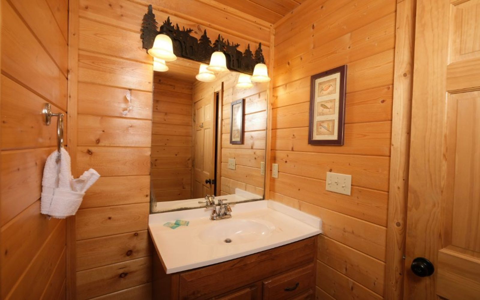 A wooden cabin bathroom with a sink, mirror, and towel rack.