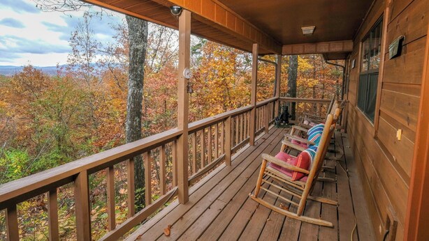 A wooden porch with rocking chairs and a view of autumn foliage. - Serenity - Pet-Friendly, Xbox, Keurig, Outdoor Hot Tub, Wood-Burning Fireplace (Pigeon Forge)
