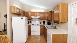 A compact kitchen with wooden cabinets, a white refrigerator, a stove, and a dishwasher. - Serenity - Pet-Friendly, Xbox, Keurig, Outdoor Hot Tub, Wood-Burning Fireplace (Pigeon Forge)