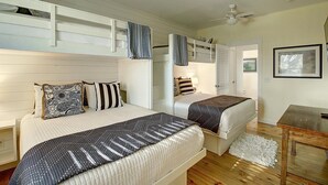 A bedroom with two beds, a bunk bed above, wooden flooring, a ceiling fan, and a framed picture on the wall. - Moonsong is in a great location, is golf cart accessible and just a short drive (Port Aransas)