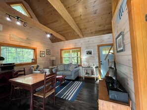 Ein gemütliches Blockhaus-Interieur mit Essbereich, einer Couch, einer Küche und einer Treppe.