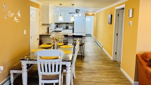 A modern kitchen with white cabinets, a dining area with a marble table, and yellow walls. - Upscale and Cozy Ocean Block Home w/ Free Parking, BBQ, Patio, Outdoor Shower (Seaside heights)
