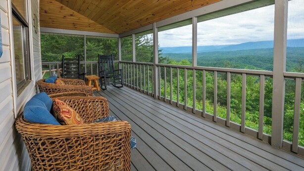 Eine überdachte Veranda mit Korbmöbeln und Blick auf eine Berglandschaft.