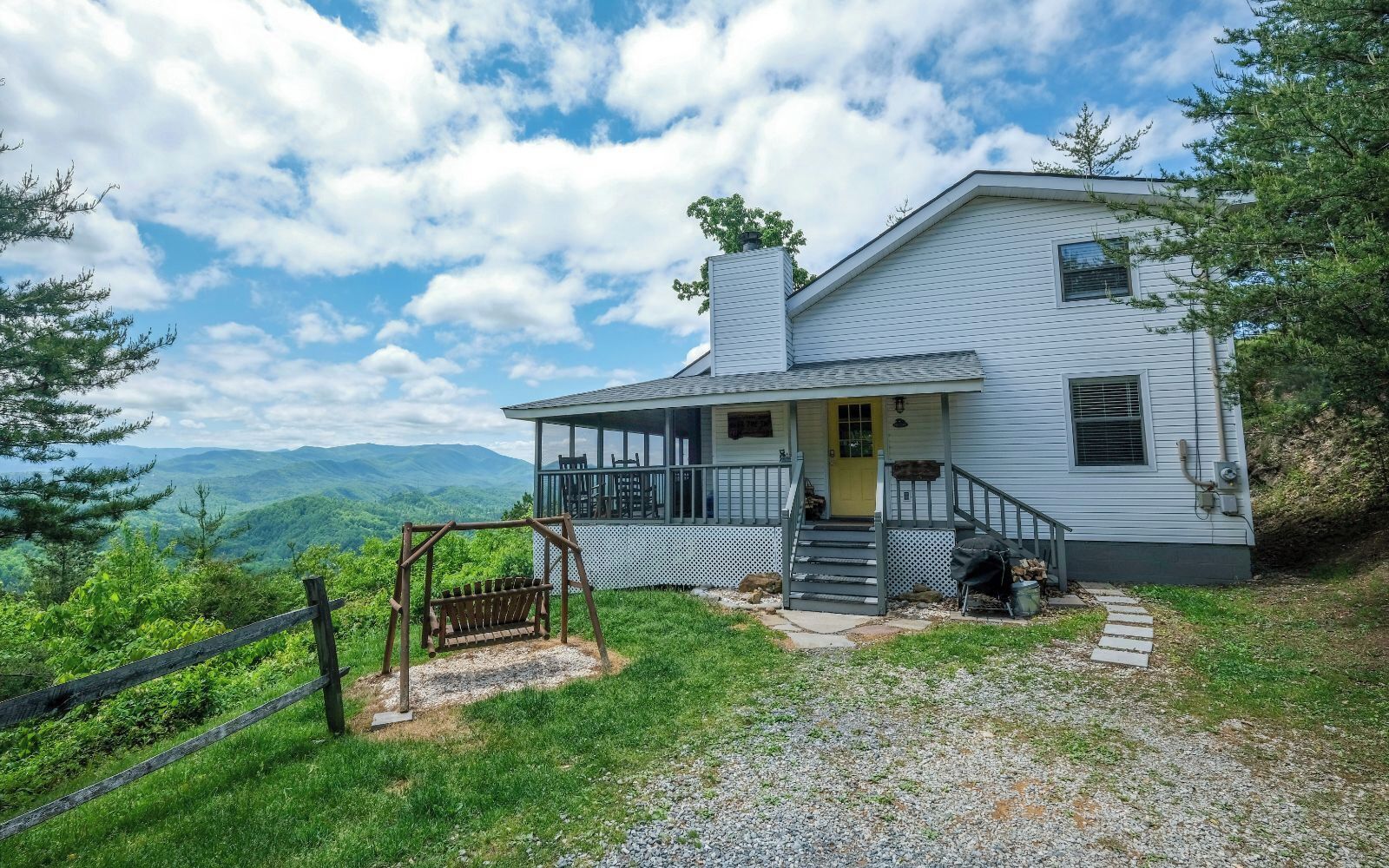 Une maison avec un porche, une balançoire et une vue sur les montagnes.