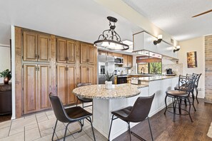 A kitchen with wooden cabinets, a granite island, and bar stools.