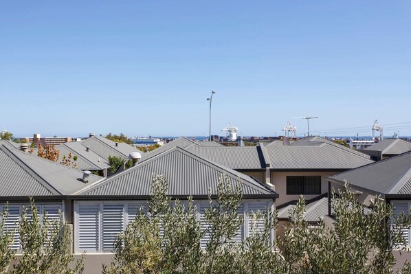 A residential area with houses featuring sloped roofs and white shutters, set against a clear blue sky.