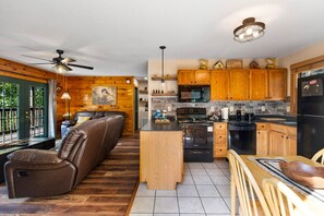 A modern kitchen with wooden cabinets, a black refrigerator, and a dining area with a wooden table and chairs.