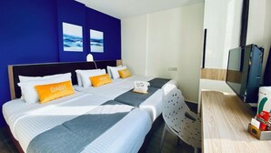 A hotel room with a bed, a desk, and a TV. - Dash Living on Mackenzie (Singapore)