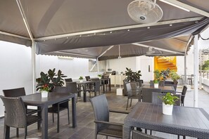 An outdoor dining area with tables and chairs, a fan, and potted plants. - Dash Living on Mackenzie (Singapore)