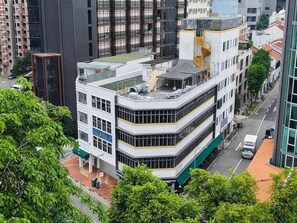 A multi-story building with a rooftop terrace, surrounded by other buildings and greenery. - Dash Living on Mackenzie (Singapore)