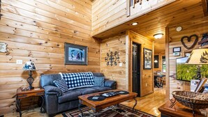 A cozy cabin interior with a checkered sofa, a wooden coffee table, and a television. - Mountain Romance - Mountain Views & Hot Tub (Sevierville)