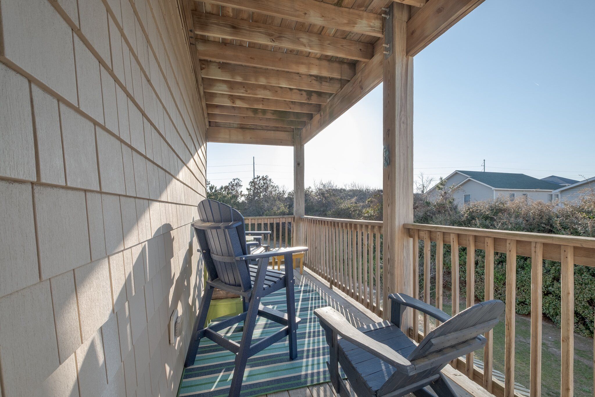 A wooden deck with two chairs and a small table, overlooking a residential area.