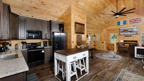 Interior de una cabaña de madera con cocina, comedor y sala de estar.