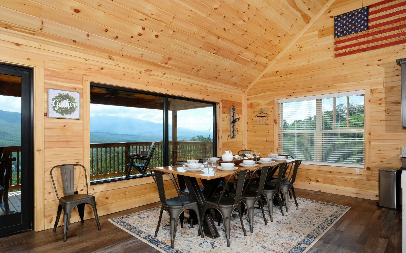Een houten chalet met een eethoek, compleet met een tafel voor zes personen, omringd door stoelen, en een groot raam met een prachtig uitzicht.