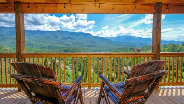Una terraza de madera con dos sillas de madera que dan a una vista panorámica de la montaña.