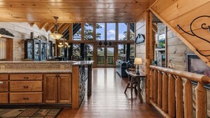 Ambiente interno in legno con cucina, zona pranzo e ampie finestre.