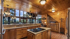 Una cucina in stile baita con mobili in legno, piani in granito, un'isola centrale e un camino in pietra.