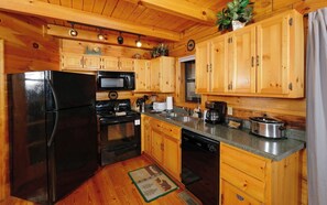A kitchen with wooden cabinets, a refrigerator, stove, microwave, and a coffee maker.