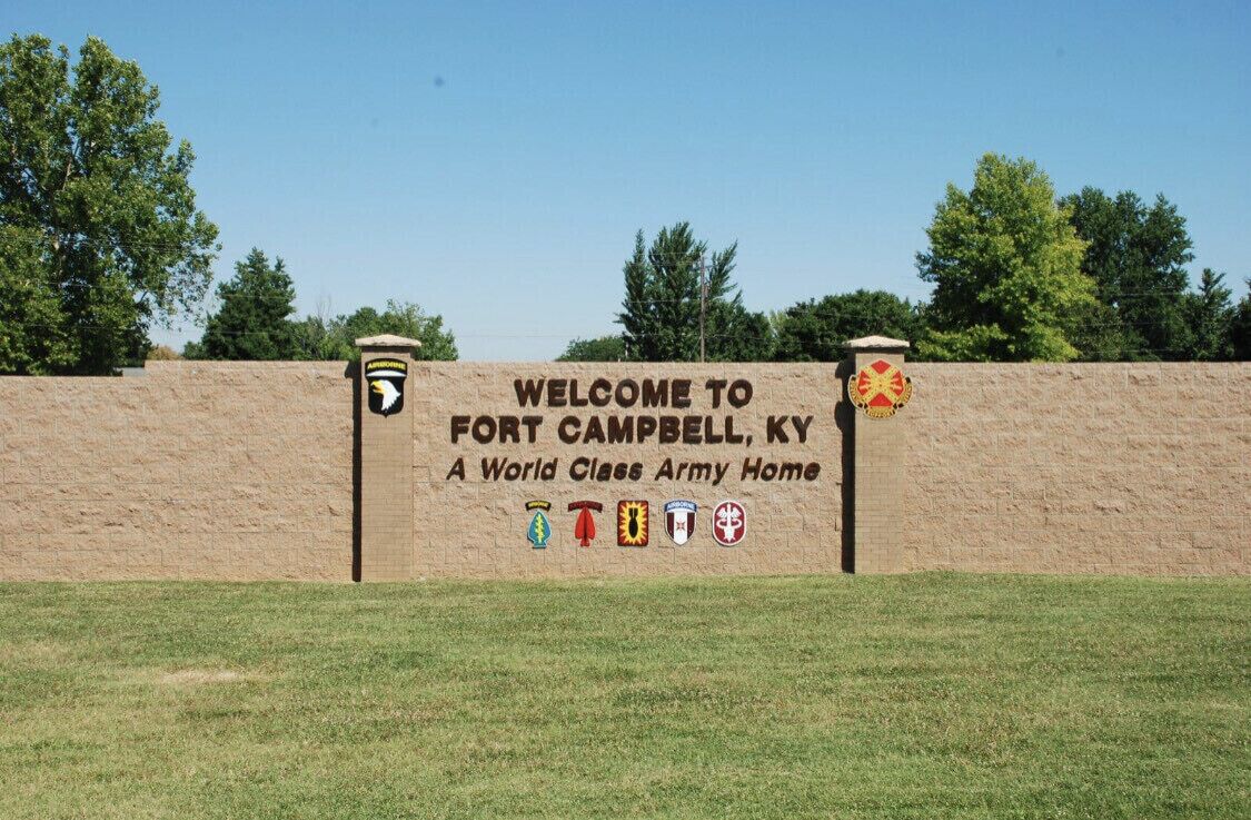 Señal de bienvenida a Fort Campbell, Kentucky, con emblemas de unidades militares.