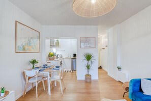 Ein modernes Wohnzimmer mit Essbereich, Küche und einem blauen Sofa.