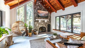 Una sala de estar acogedora con chimenea de piedra, vigas de madera, ventanas amplias y asientos confortables.