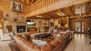 A spacious living room with a fireplace, leather sofas, and a television.