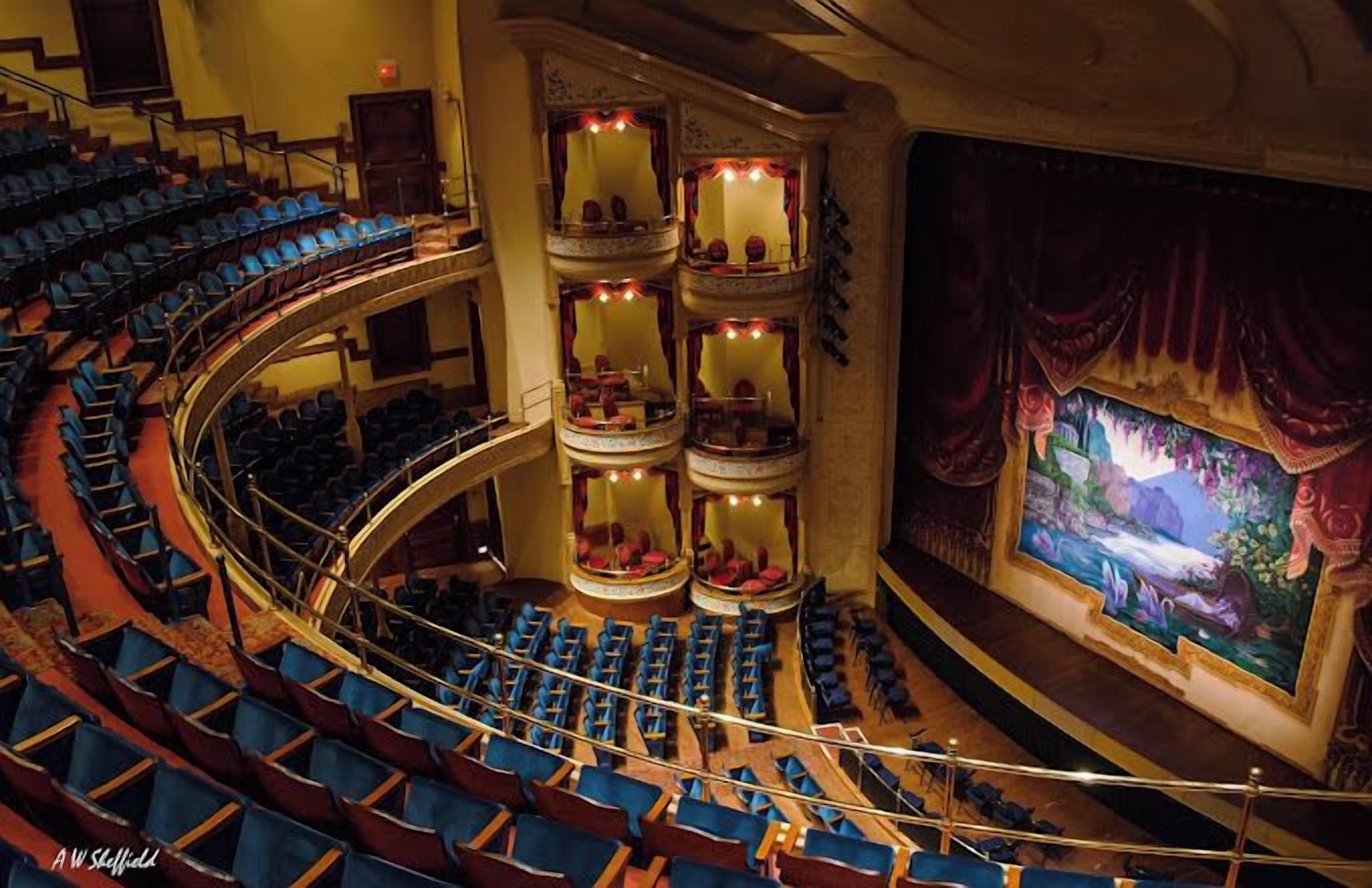Un théâtre doté de plusieurs balcons, d’une scène centrale et de rangées de sièges bleus.